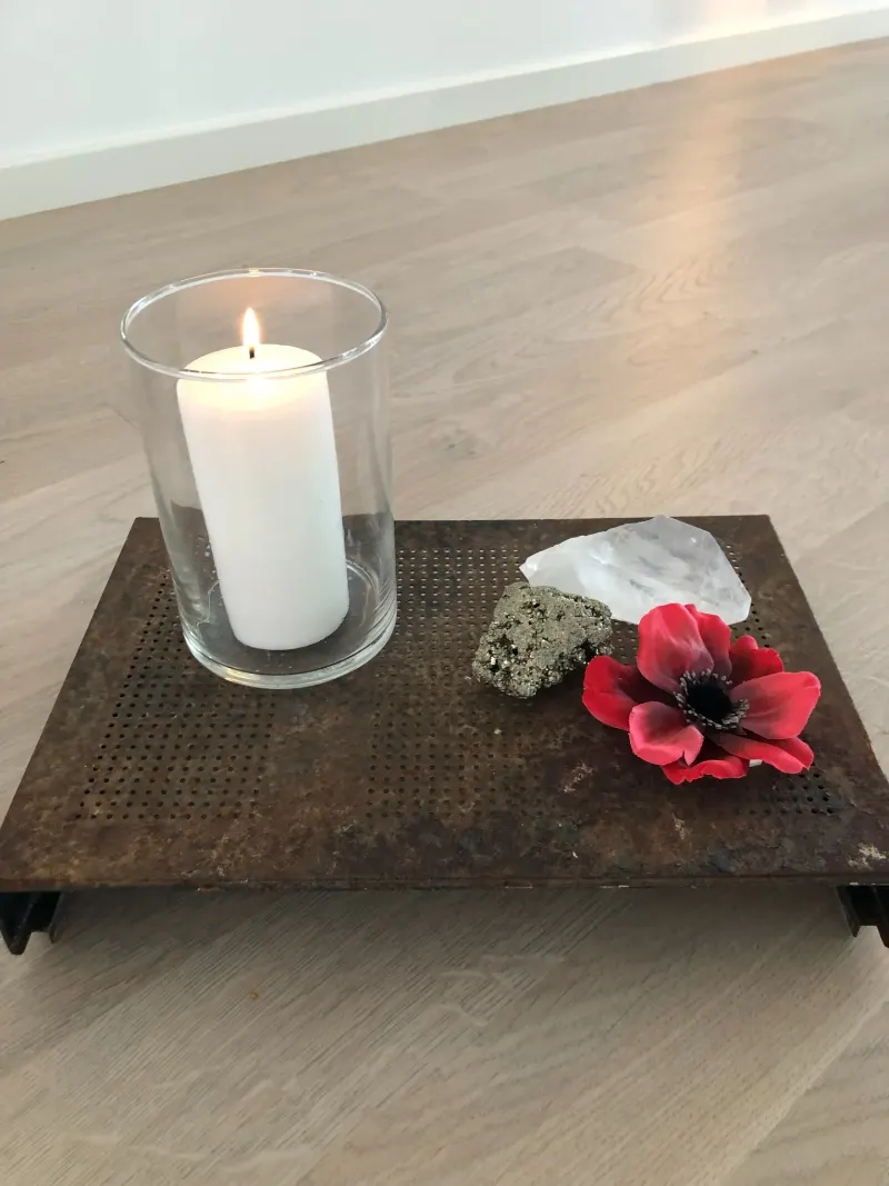 Lys i glas og en rød blomst